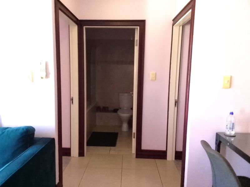 A central hallway with tiled flooring providing access to adjacent rooms, including a view into a bathroom with a toilet.