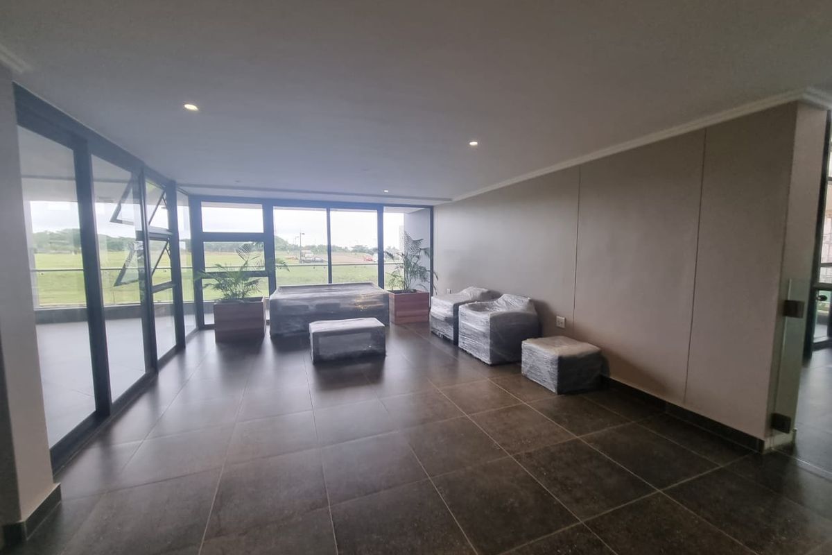 Spacious living area featuring large format floor tiles, recessed lighting, and expansive glass sliding doors providing ample natural light and outdoor views.