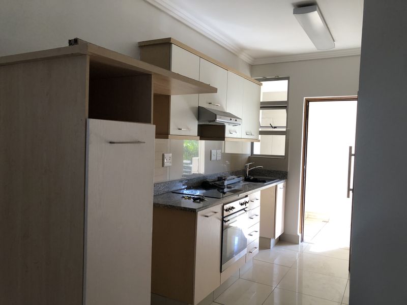 A functional kitchen featuring built-in cabinetry, granite countertops, integrated oven and hob, and direct access to an outdoor area.