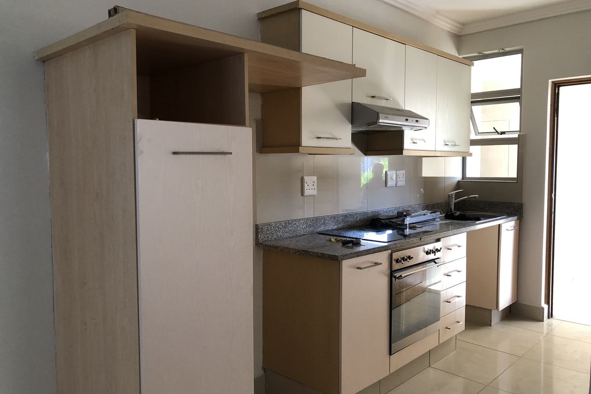 A functional kitchen featuring built-in cabinetry, granite countertops, a stainless steel oven, and an electric hob with an extractor fan.