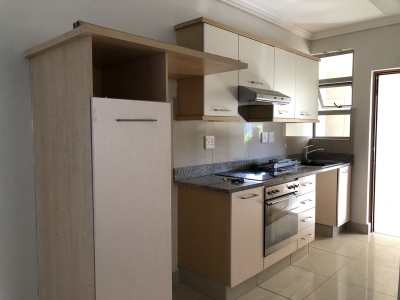 A functional kitchen featuring built-in cabinetry, granite countertops, a stainless steel oven, and an electric hob with an extractor fan.