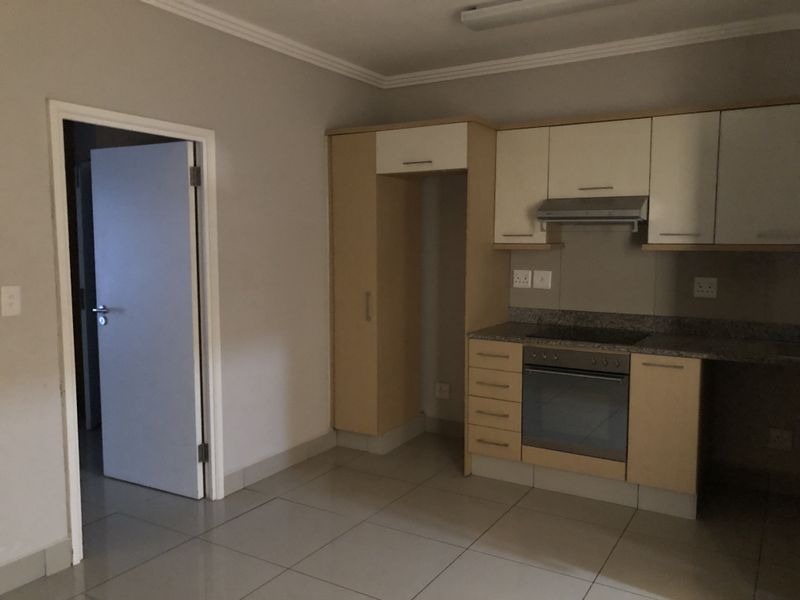 A functional kitchen featuring built-in cabinetry, granite countertops, an integrated oven and hob, and tiled flooring.