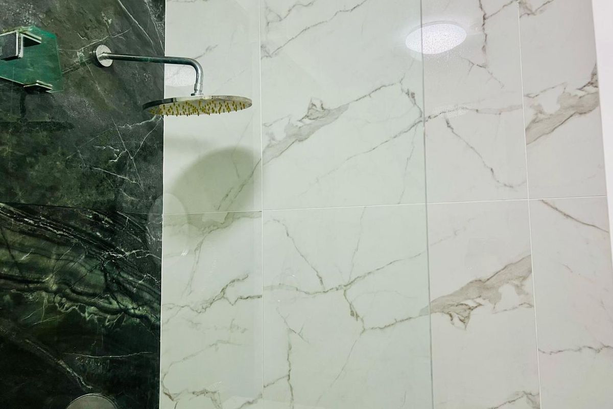 A modern shower enclosure featuring high-contrast marble-effect wall tiling and a contemporary rainfall shower head.