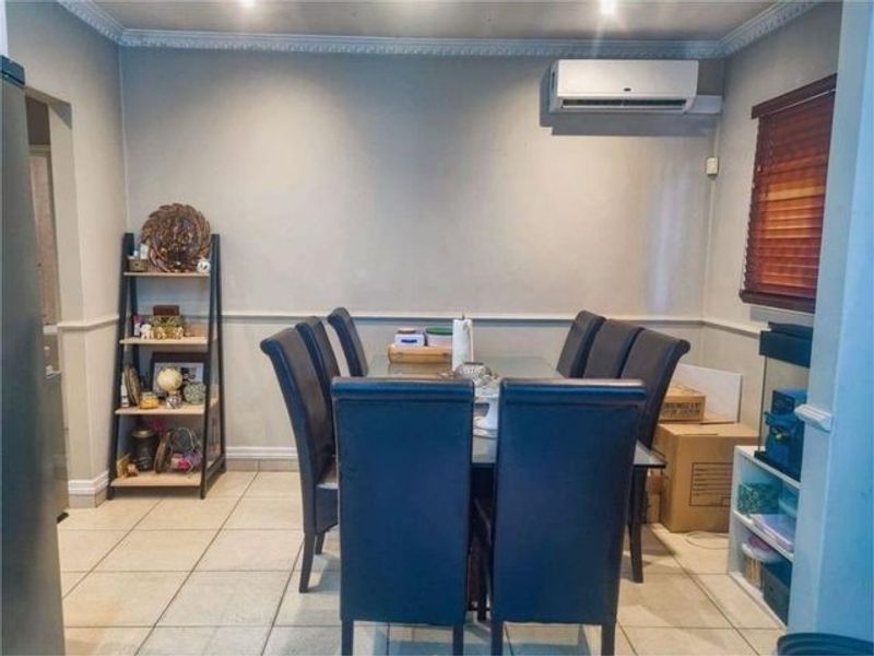 A dining room featuring tiled flooring, crown molding, chair rail detailing, and a wall-mounted air conditioning unit.