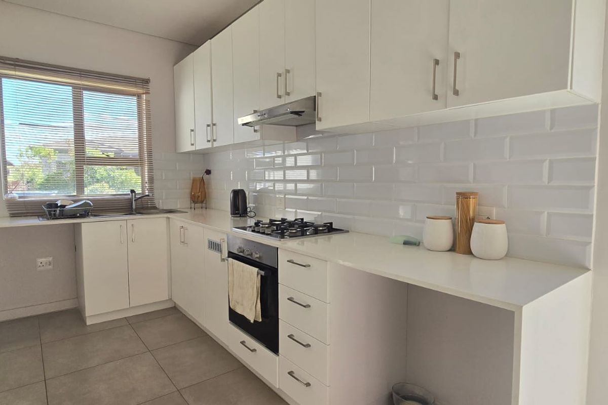 Modern kitchen featuring white cabinetry, subway tile backsplash, gas hob, electric oven, and tiled flooring with ample counter space.