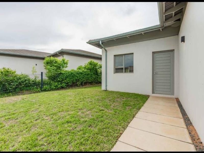 A well-maintained rear exterior view featuring a paved walkway, manicured lawn, and clean building facade with modern finishes.