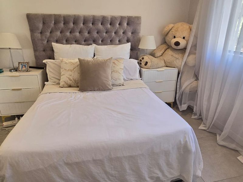A well-maintained bedroom featuring neutral tiled flooring and a modern interior door, offering a clean and comfortable living space.