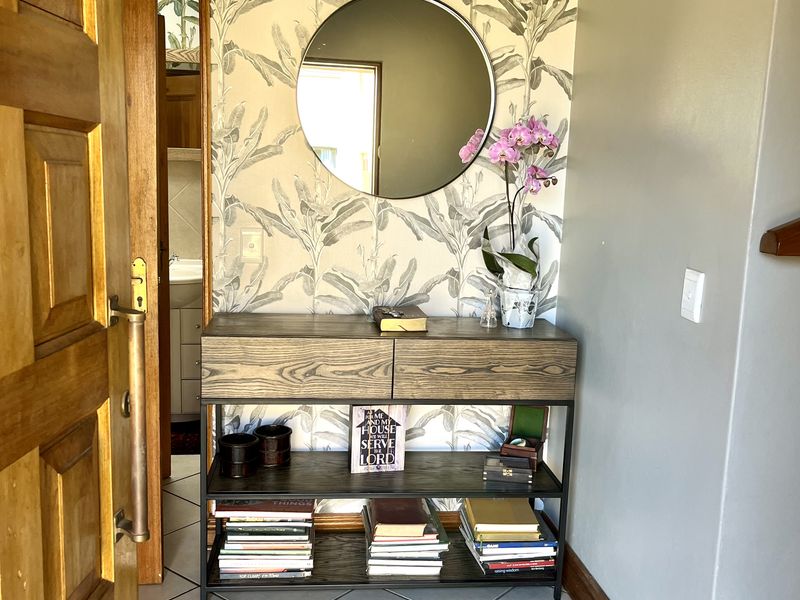 A welcoming entrance hall featuring tiled flooring, a solid wooden door, and decorative wallpaper, providing a clean and well-maintained transition into the home.