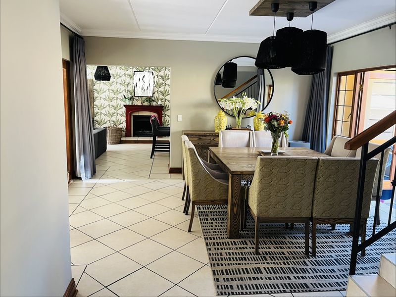 Spacious open-plan dining area featuring tiled flooring, a feature fireplace in the adjacent living space, and modern pendant lighting.