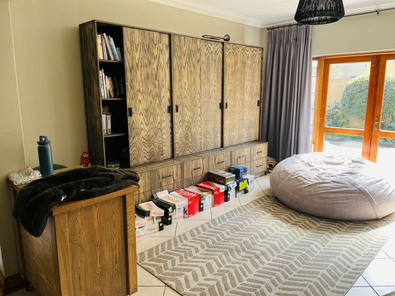 A living area featuring extensive built-in wooden cabinetry, tiled flooring, and large wooden sliding doors providing access to the garden.