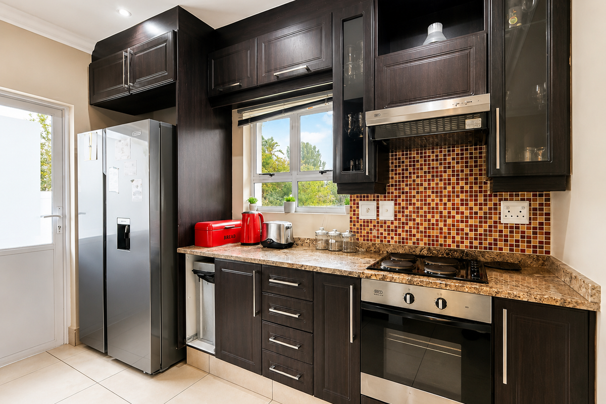 A well-maintained kitchen featuring dark wood cabinetry, granite countertops, a mosaic tile backsplash, and integrated stainless steel appliances.