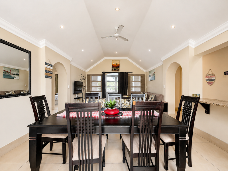Spacious dining room featuring a vaulted ceiling with recessed lighting, tiled flooring, and elegant archways leading to adjacent living areas.