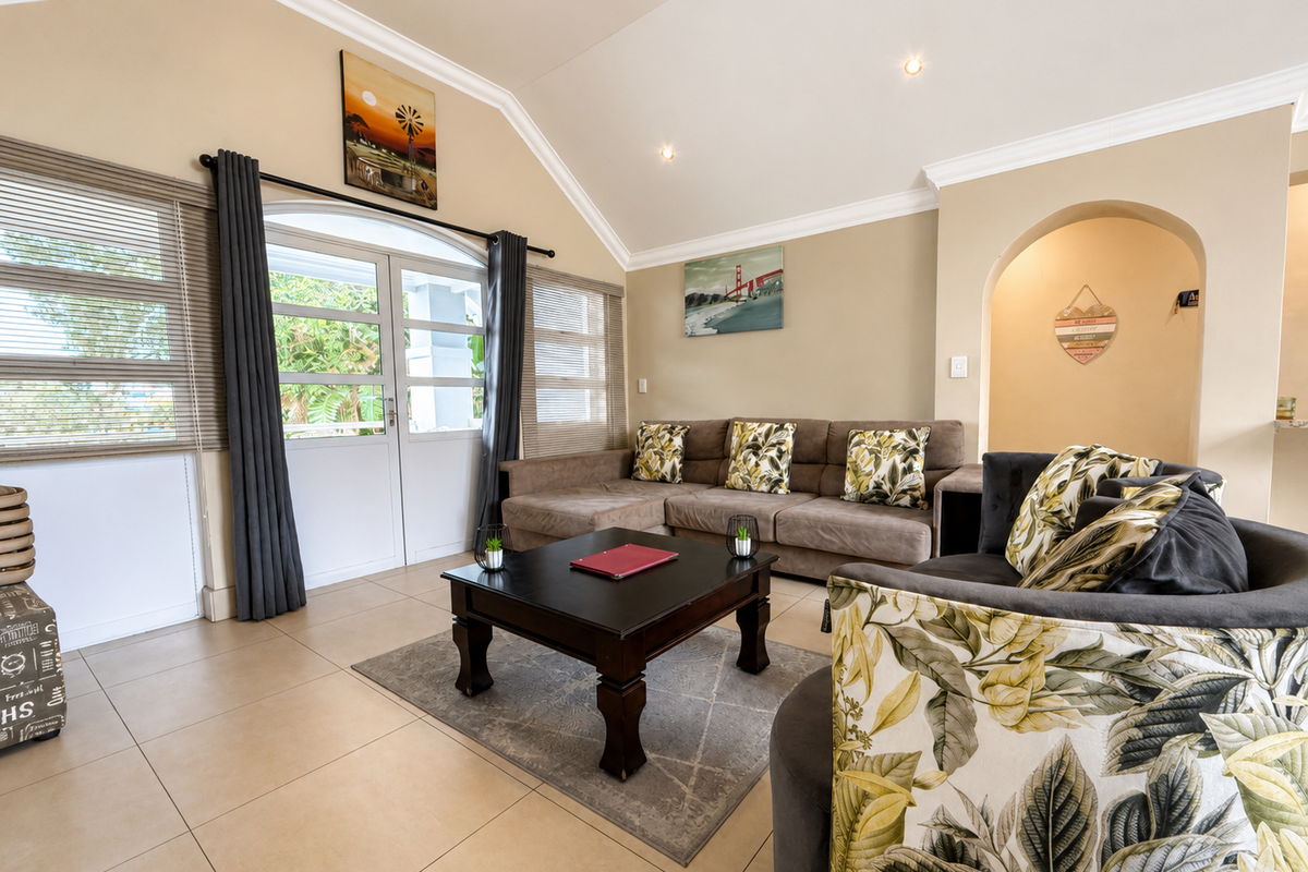 Spacious living room featuring a vaulted ceiling, tiled flooring, and an elegant archway leading to adjacent areas, with natural light from double glass doors.