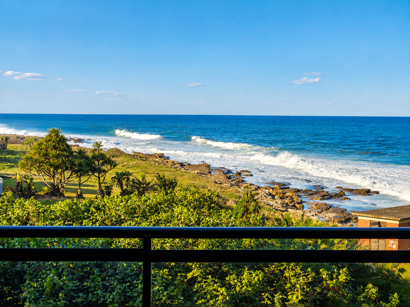 Stunning elevated ocean view overlooking the coastline, rocky shore, and lush coastal vegetation from a private balcony.