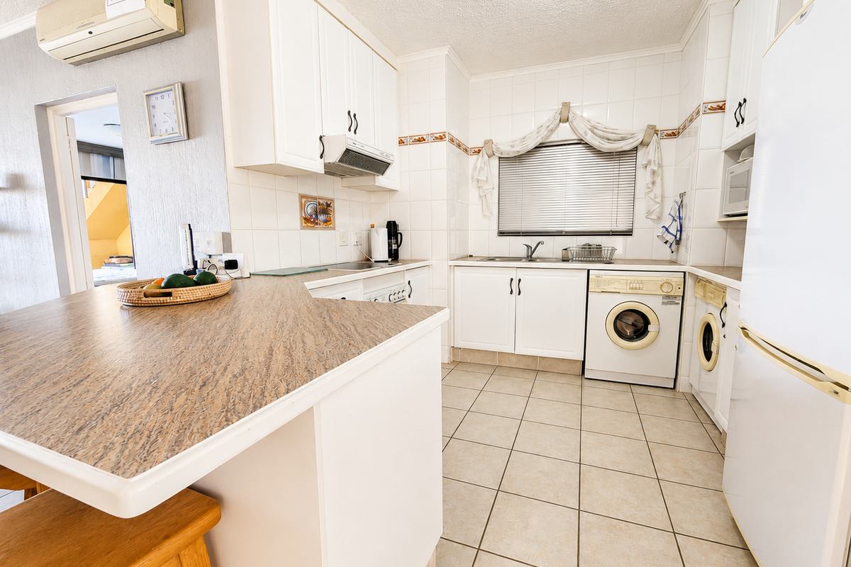 A functional kitchen featuring white cabinetry, laminate countertops, tiled backsplash, and integrated appliances, including a built-in oven and extractor fan.