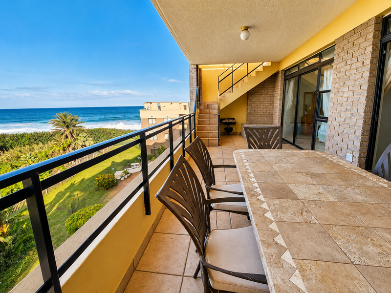 Spacious covered balcony featuring tiled flooring, a metal balustrade, and direct access to the interior, offering scenic ocean views.