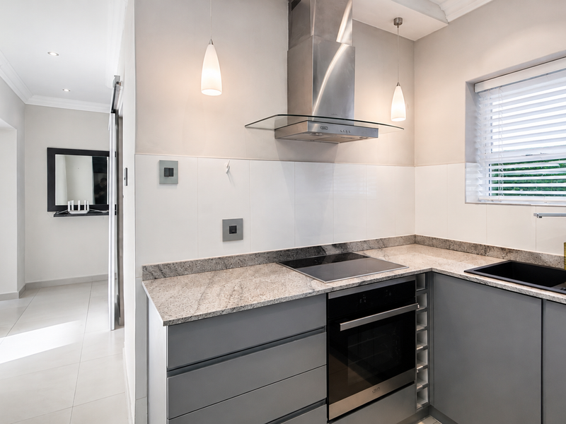 Modern kitchen featuring sleek grey cabinetry, granite countertops, integrated stainless steel appliances, and a clean, contemporary aesthetic with ample natural light.