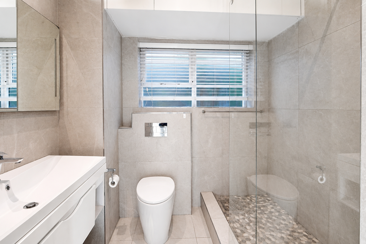 Modern bathroom featuring a wall-mounted vanity, concealed cistern toilet, and a spacious walk-in shower with a glass screen and pebble tile flooring.