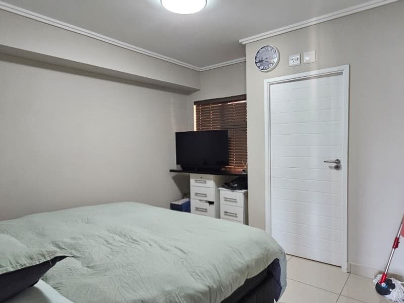 A well-maintained bedroom featuring tiled flooring, built-in storage, and neutral wall finishes, providing a clean and functional living space.