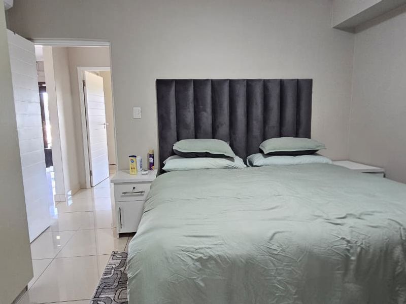 A well-maintained bedroom featuring neutral wall tones, tiled flooring, and a built-in wardrobe, offering a clean and functional living space.