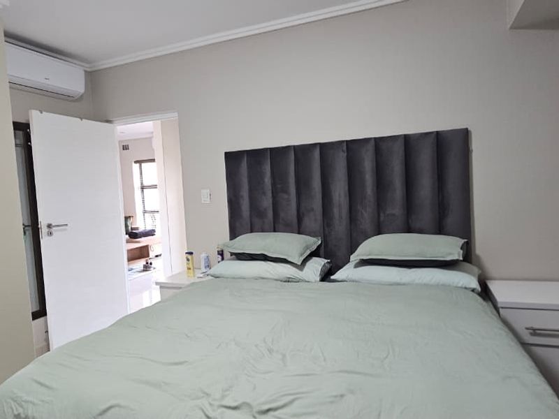 A well-maintained bedroom featuring a built-in wardrobe, split-system air conditioning unit, and neutral wall finishes.