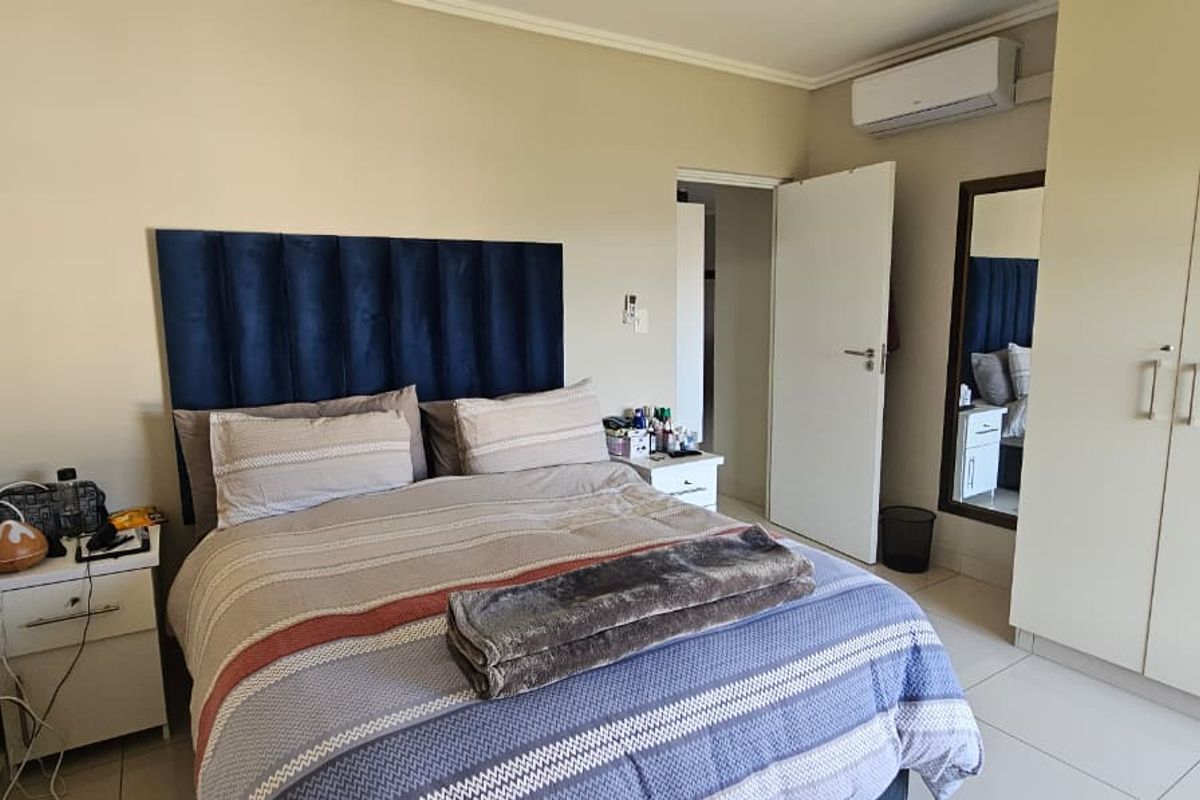 A well-maintained bedroom featuring built-in cupboards, tiled flooring, and a wall-mounted air conditioning unit.