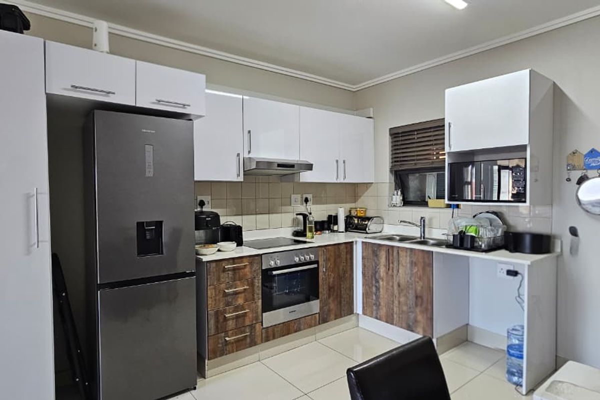Modern kitchen featuring two-tone cabinetry, built-in oven and hob, extractor fan, and tiled flooring with a functional layout.