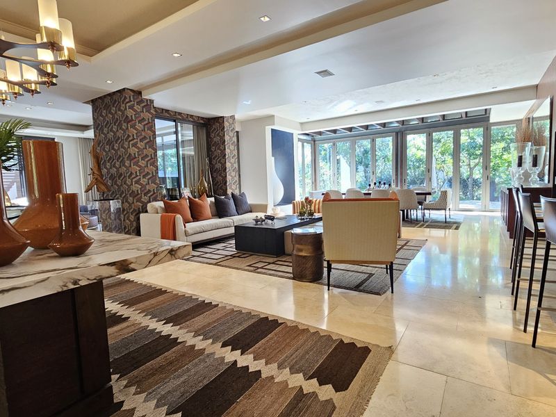 Spacious open-plan living and dining area featuring polished marble flooring, recessed lighting, and large bi-fold glass doors opening to the garden.