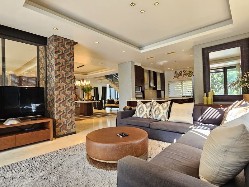 Spacious open-plan living area featuring a modern kitchen, coffered ceilings with recessed lighting, and a stylish patterned feature wall.