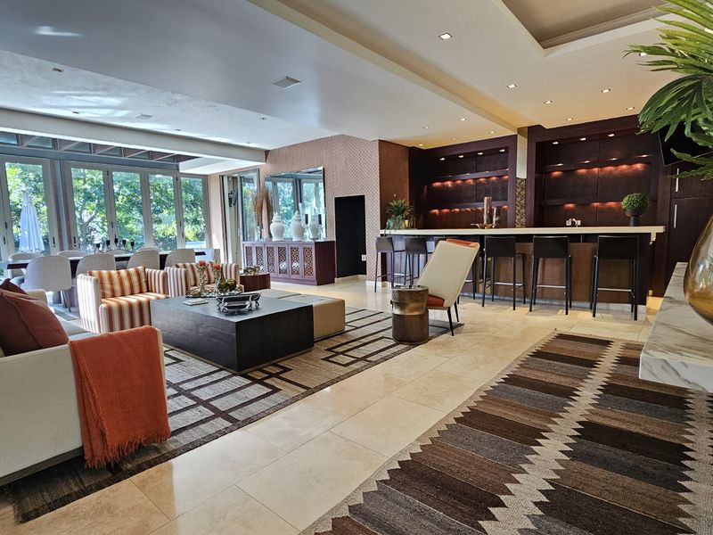 Spacious open-plan living area featuring a sophisticated built-in bar, stone flooring, and large bi-fold doors that provide seamless access to the outdoor space.
