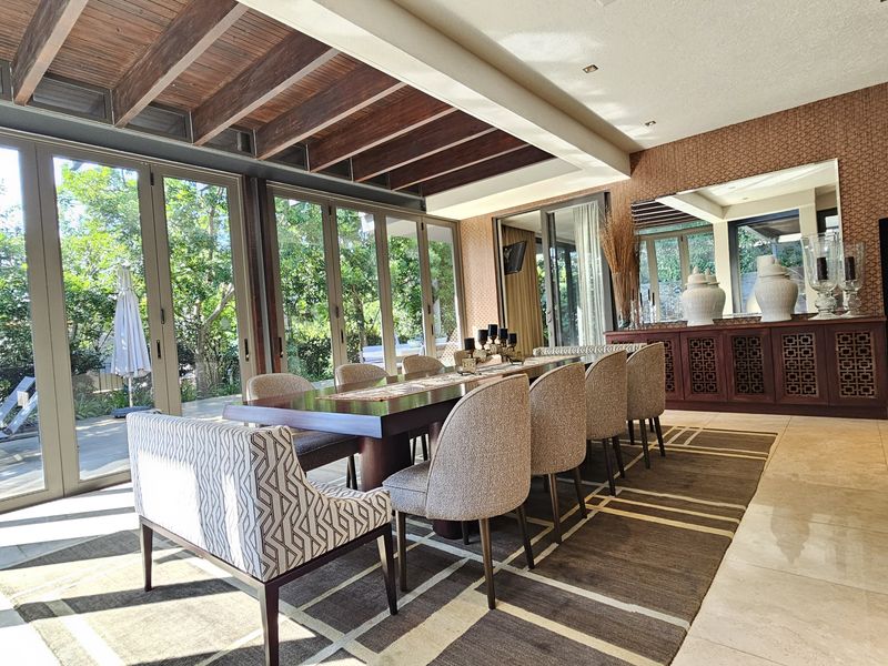 Spacious dining room featuring exposed timber ceiling beams, large aluminium sliding doors opening to the garden, and elegant built-in cabinetry.