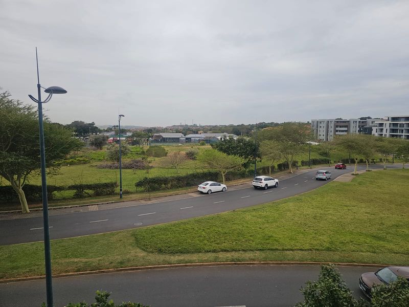 An elevated view overlooking the surrounding neighbourhood, featuring local roads, green spaces, and nearby residential apartment buildings.