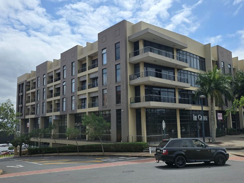 A modern multi-story apartment building featuring contemporary architectural design, large glass windows, and private balconies, situated in a well-maintained urban setting.