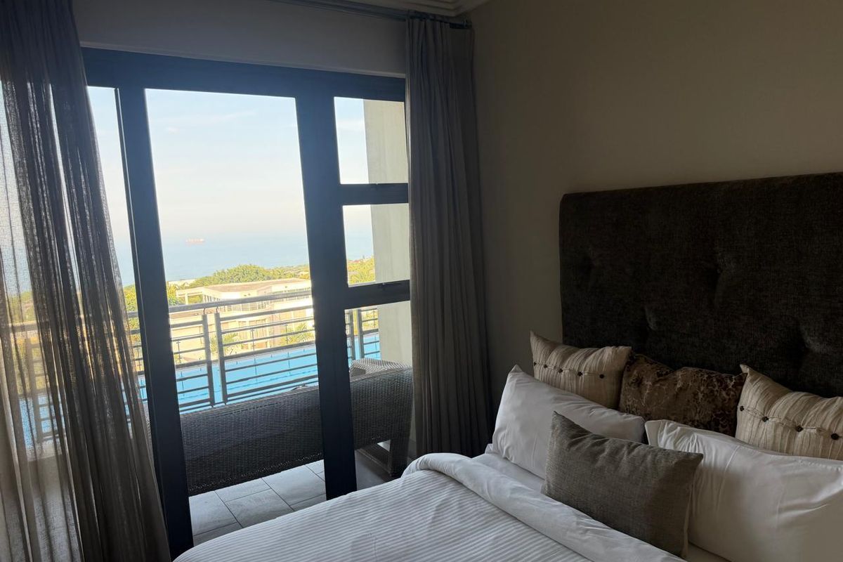 A well-maintained bedroom featuring a large sliding glass door that provides direct access to a balcony with scenic views.