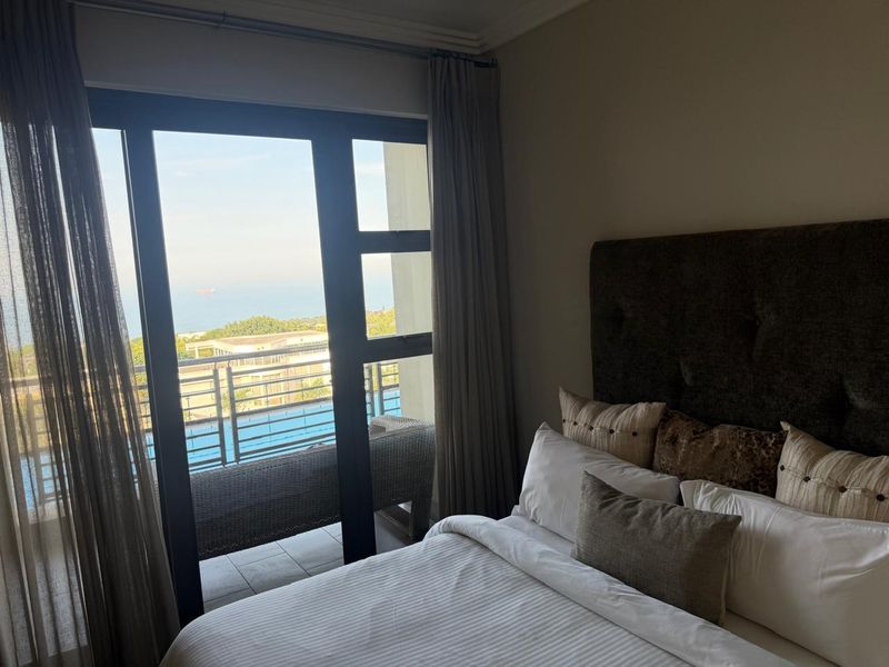 A well-maintained bedroom featuring a large sliding glass door that provides direct access to a balcony with scenic views.