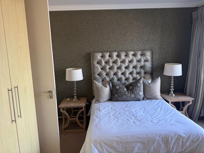 A well-maintained bedroom featuring a built-in wardrobe, textured feature wall, and classic coving detail.