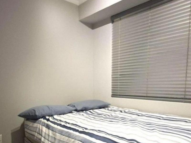 A compact bedroom featuring neutral walls, tiled flooring, and fitted venetian blinds.