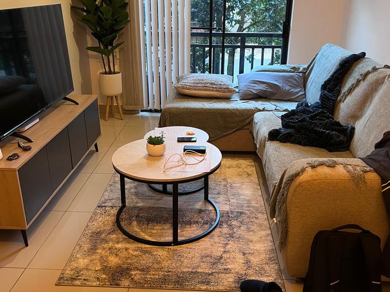 A comfortable living room featuring tiled flooring and a large sliding glass door with vertical blinds, providing access to an outdoor balcony area.