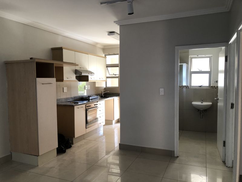 An open-plan kitchen area featuring built-in cabinetry, granite countertops, and an integrated oven, with an adjacent bathroom visible through the doorway.