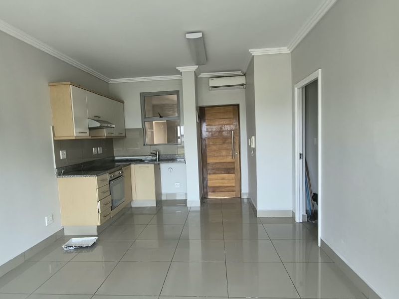 An open-plan living and kitchen area featuring tiled floors, built-in cabinetry with granite countertops, and an integrated oven.