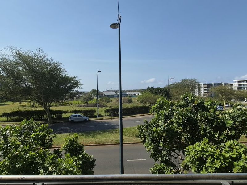 An elevated view overlooking a suburban street, green space, and surrounding apartment buildings.