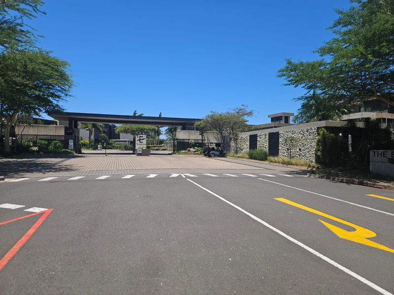 View of the secure entrance gatehouse and paved driveway leading into the residential estate.