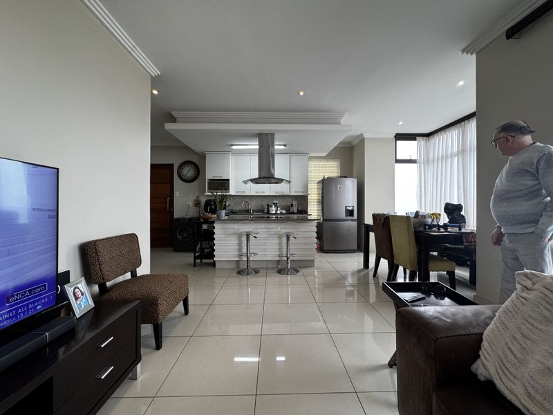 Spacious open-plan living area featuring a modern kitchen with a central island, sleek cabinetry, and polished tiled flooring throughout.