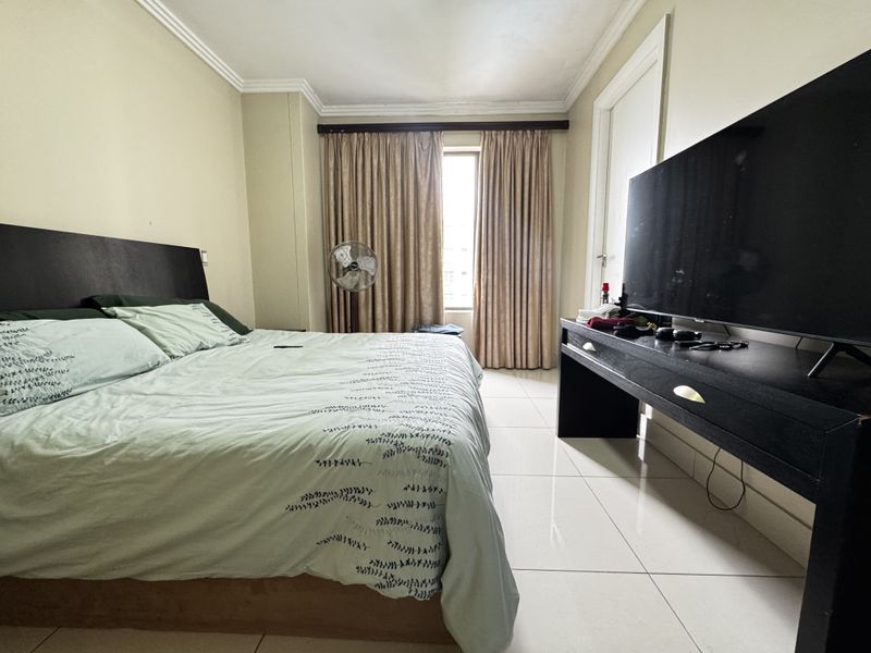A bedroom featuring tiled flooring and crown molding, providing a functional space with natural light from the window.