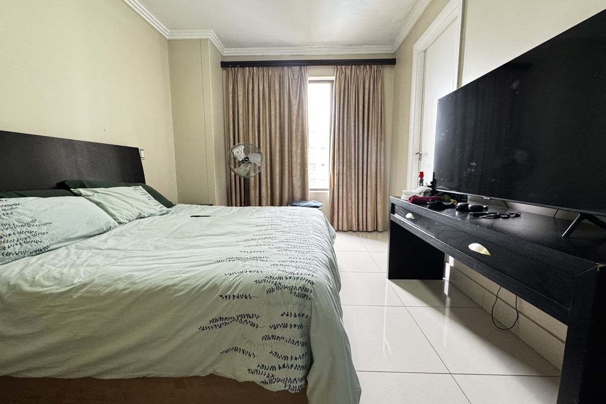 A bedroom featuring tiled flooring and crown molding, providing a functional space with natural light from the window.