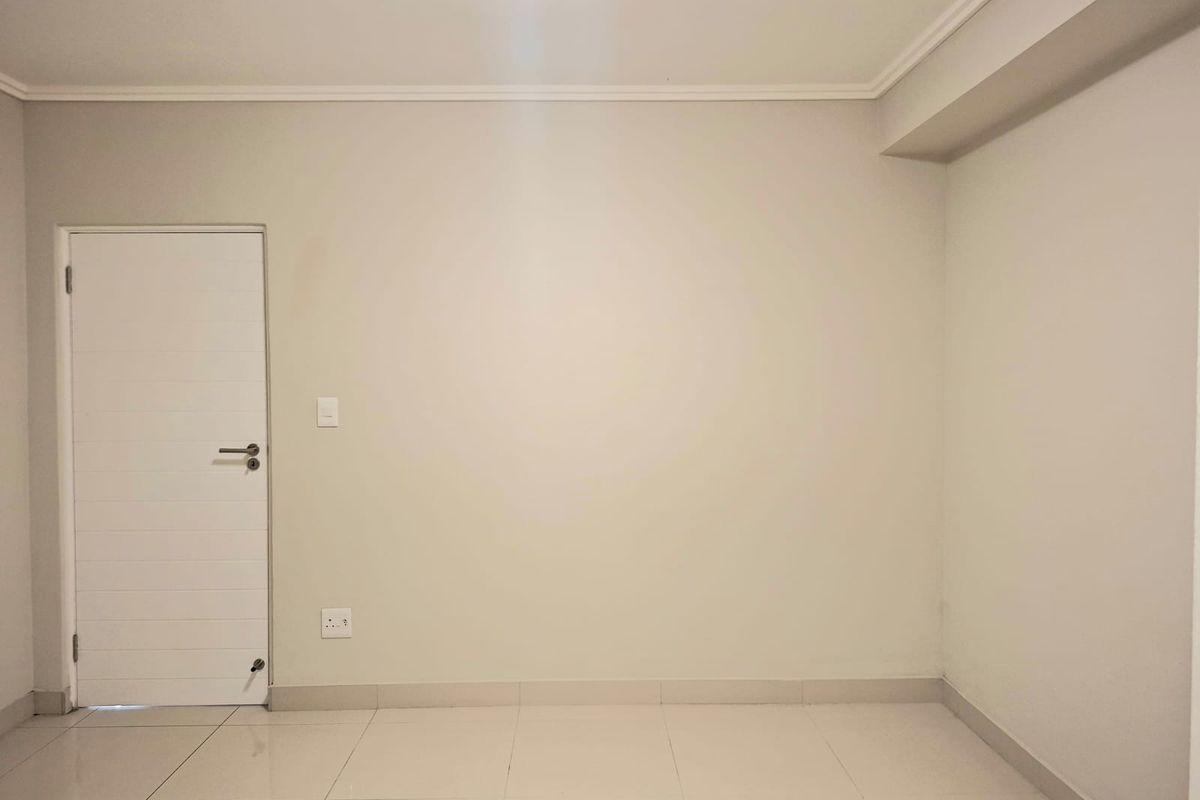 A clean, empty bedroom featuring neutral walls, tiled flooring, and simple architectural detailing, providing a blank canvas for personalization.