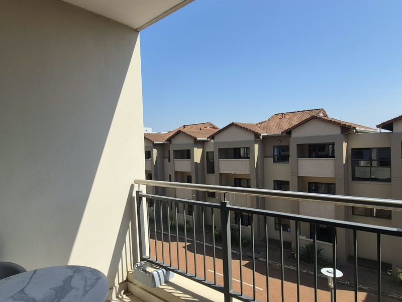 A private balcony featuring a metal balustrade with views overlooking the apartment complex grounds.