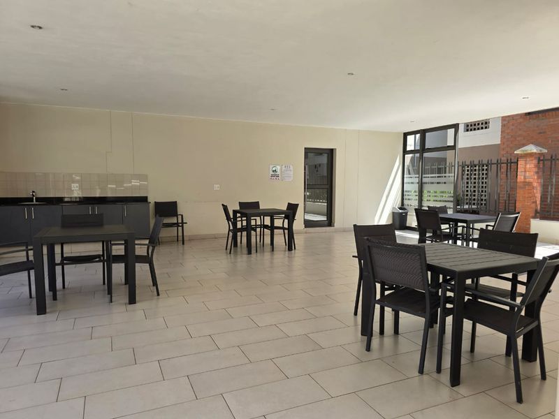 A spacious covered patio area featuring tiled flooring, recessed lighting, and a built-in kitchenette with granite countertops, ideal for outdoor entertaining.