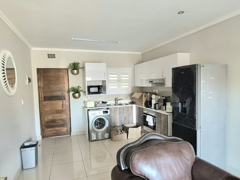 Open plan kitchen area featuring modern cabinetry, built-in oven, extractor fan, and tiled flooring, seamlessly integrated with the living space.