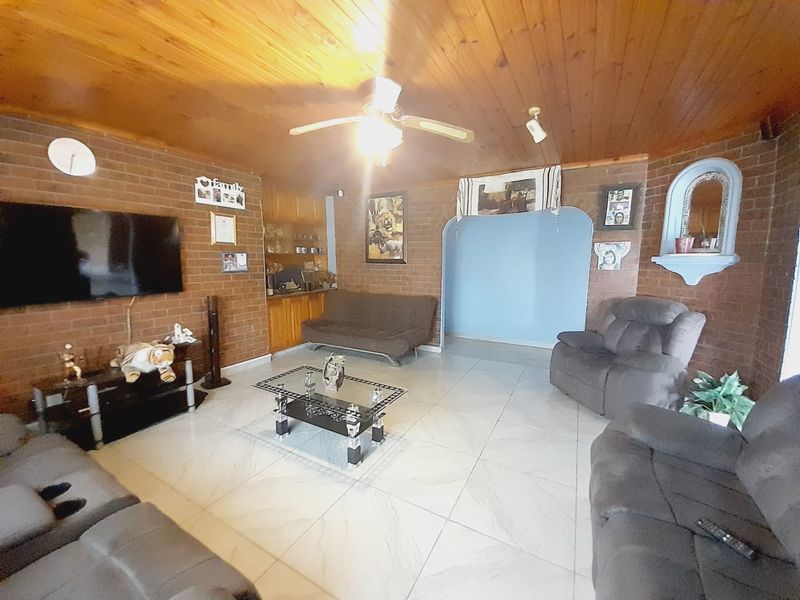 Spacious living room featuring exposed brick walls, a timber ceiling, tiled flooring, and a built-in cabinetry unit.